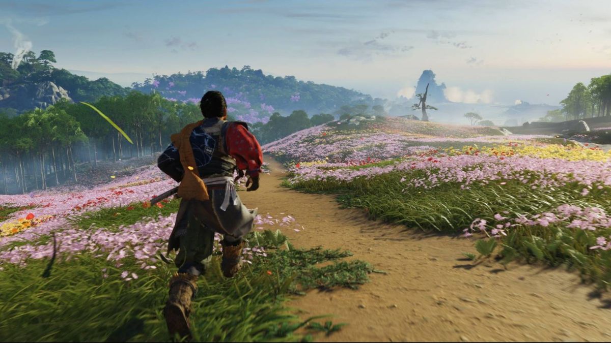 Ghost of Tsushima director&#039;s cut screenshot of Jin walking across a flower-filled meadow