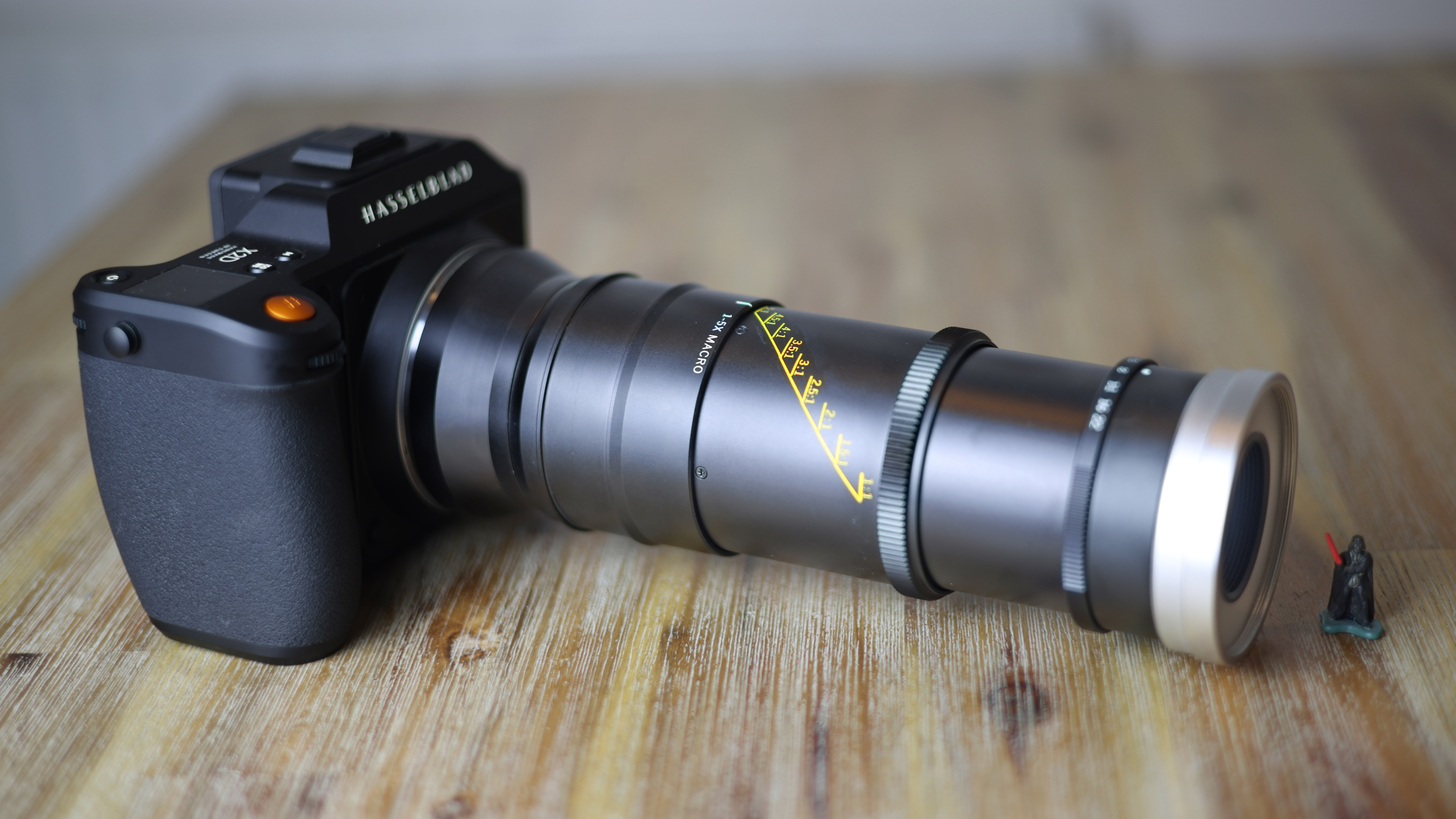 Mitakon 55mm f/2.8 1-5x Macro lens on a Hasselblad camera next to a miniature Darth Vader figure