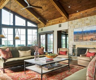 living room with stone walls and wooden ceiling with steel framed floor to ceiling glass windows