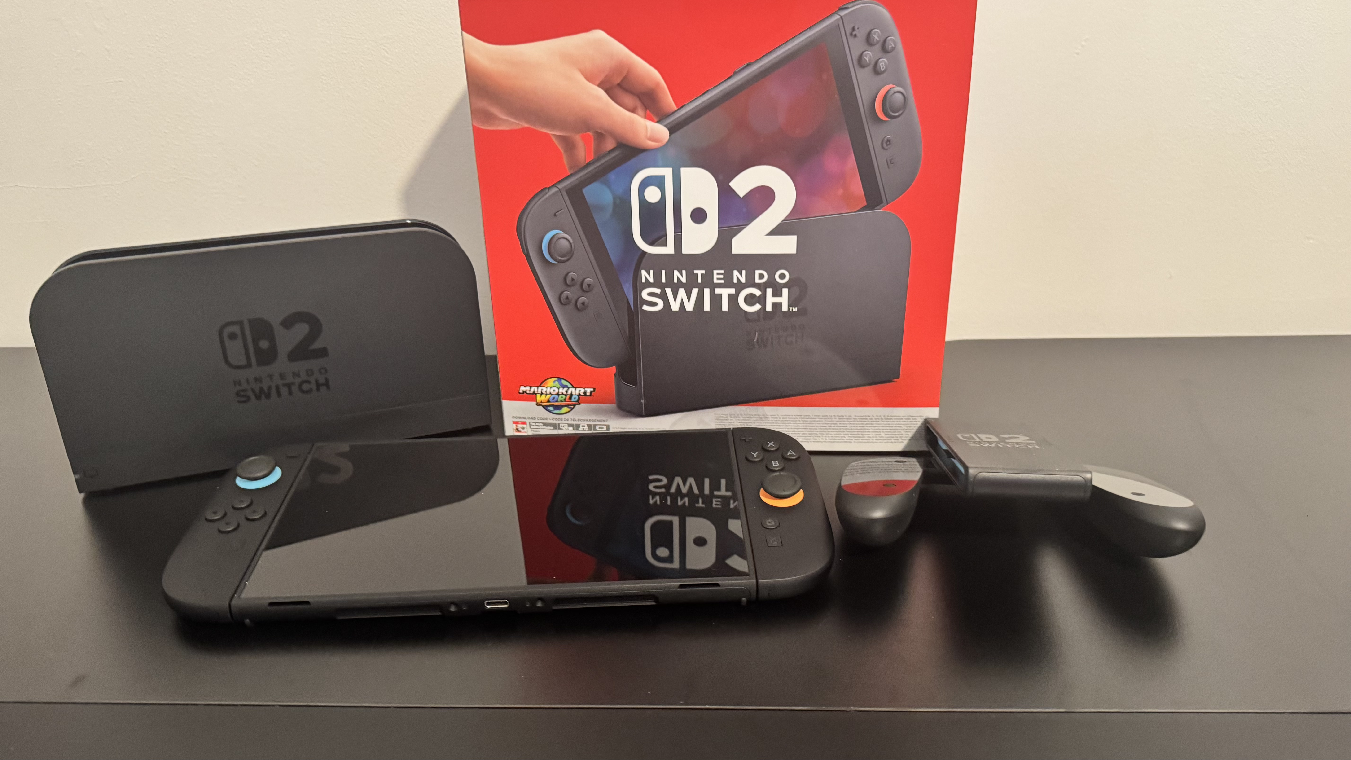 A picture of Nintendo Switch 2 dock beside the console and the Switch 2 box behind it