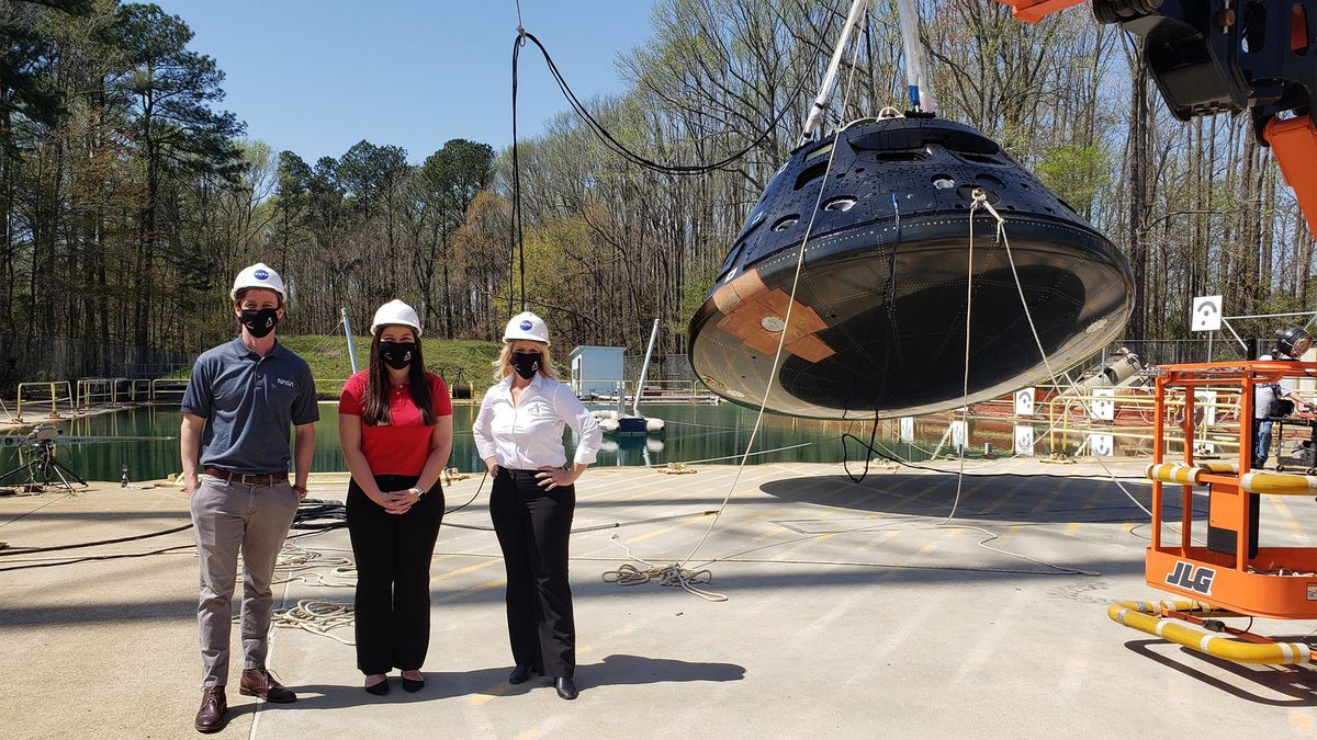 (From left) Jacob Putnam, Ally Olney and Debbie Korth pose with the Orion test article in front of the Hydro Impact Basin at NASA's Langley Research Center.