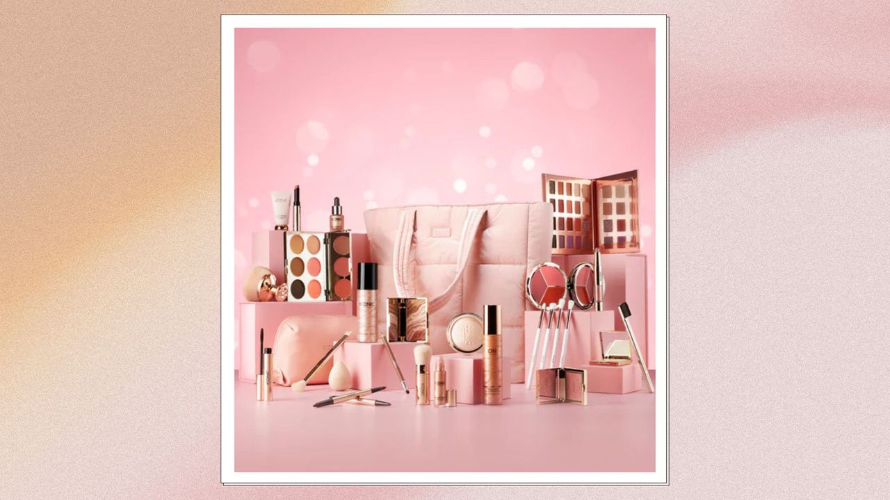 An iconic london advent calendar pictured with various makeup items around it on a pink backdrop