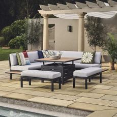 John Lewis Platform 8-Seater Corner Garden Dining Lounge Set with Height-Adjustable Table in grey next to an outdoor swimming pool