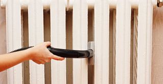 Person showing how to clean radiators with a vacuum