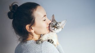 Woman cuddling devon rex cat