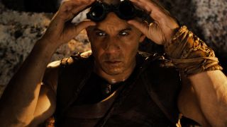 Still from the movie series The Chronicles of Riddick. Here we see Riddick (bald man) lifting up his dark goggles to reveal two glowing white eyes. This is known as eyeshine and helps him to see in the dark, but also means he’s very sensitive to light.