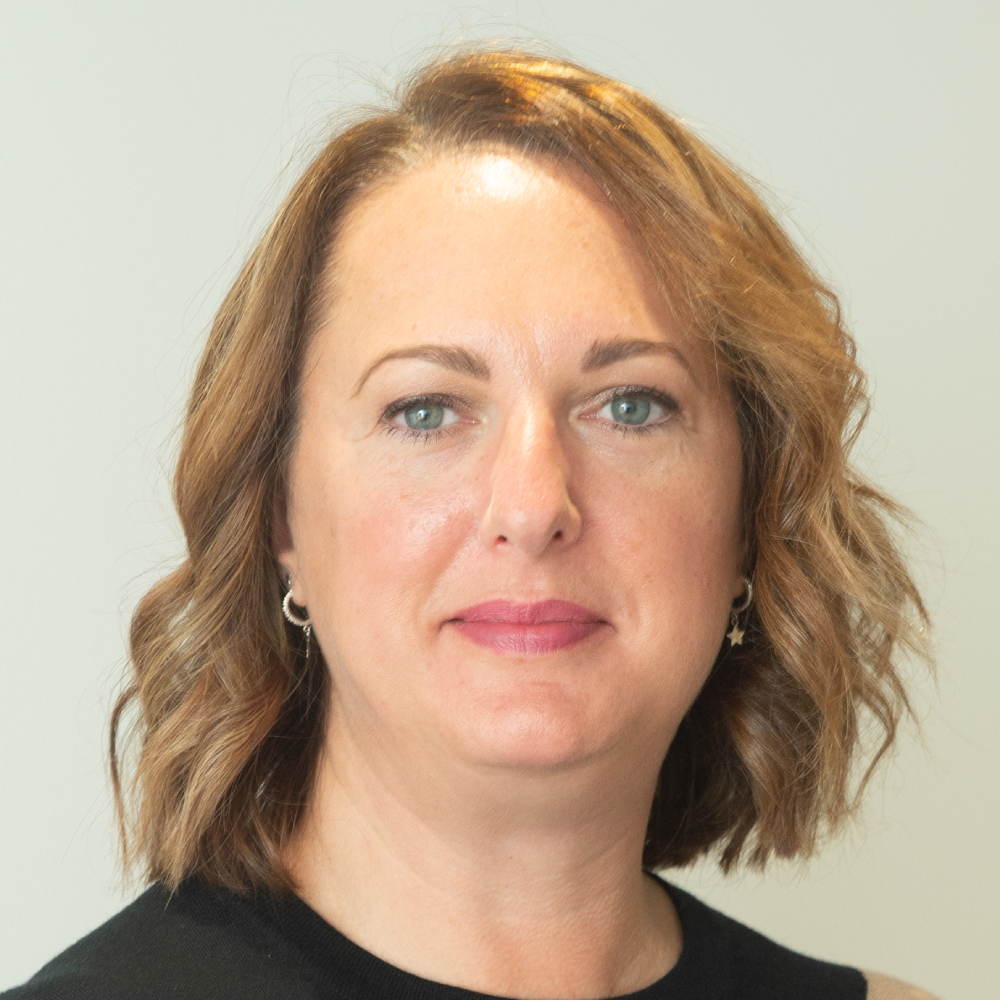 female with short dark strawberry blonde bob smiling to camera