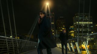 Andrew Koji as Jason, holding a phone to his ear as he stands on a London bridge, in 'Black Doves.'