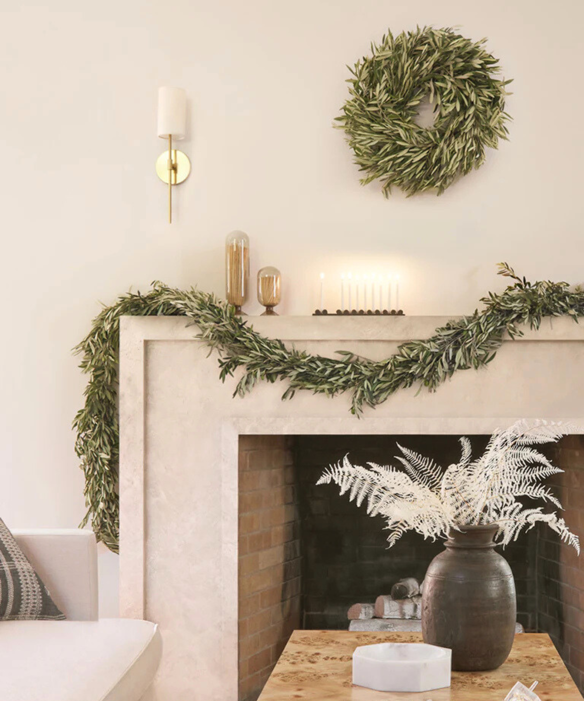 a minimalist living room with garland draped over the mantel and a matching wreath
