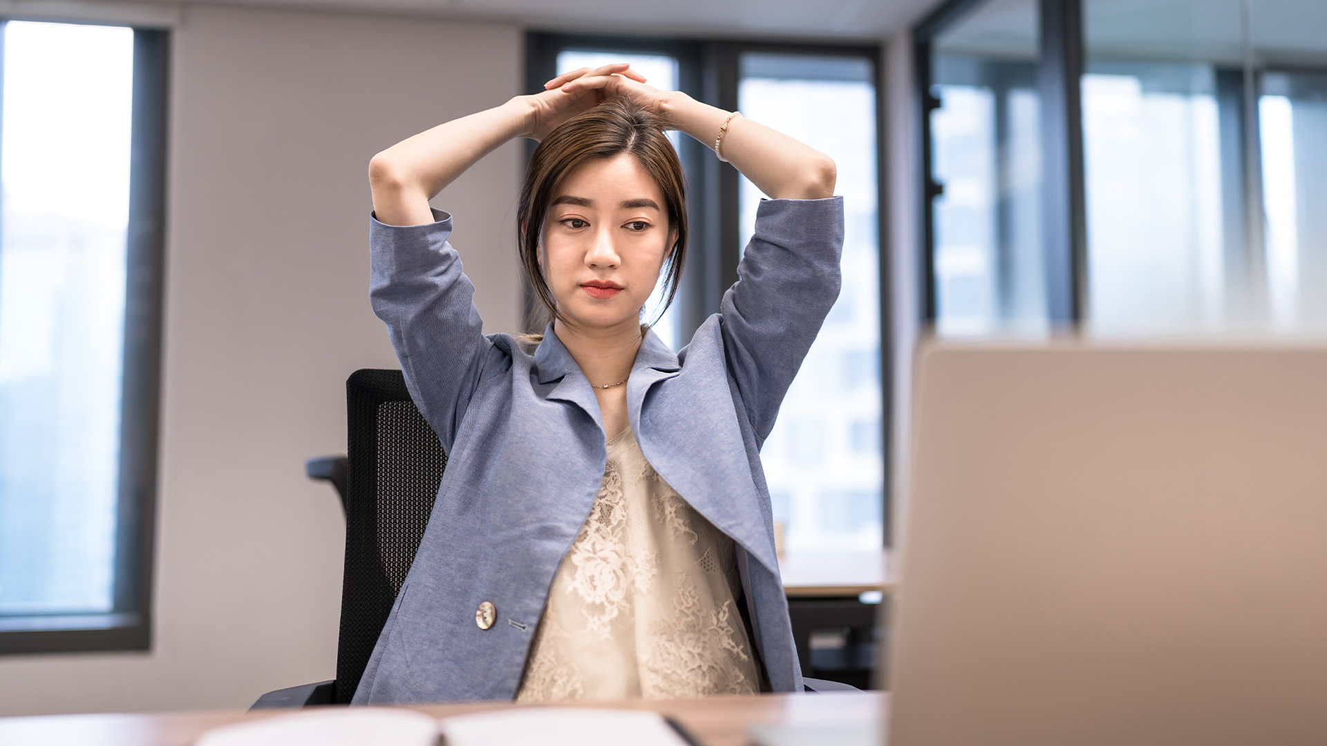 AI workslop concept image showing stressed female office worker with hands on head while working on laptop fixing low quality work. 