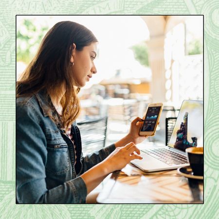 A woman seated at her desk reviews her finances on a mobile app.