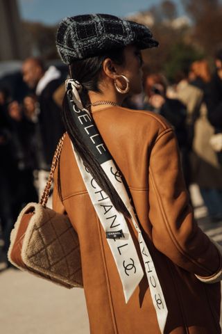 Person in beret and chanel hair scarf at Paris fashion week