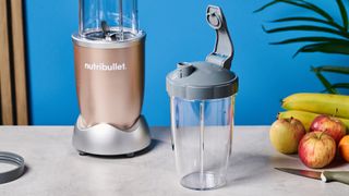 a champagne nutribullet pro 900w with fruit in the shot and a blue background