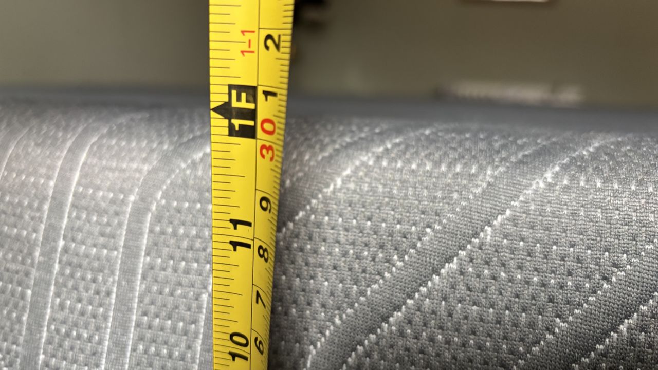 A measuring tape measures the height of the fully-expanded EGOHOME Black 12" Mattress.