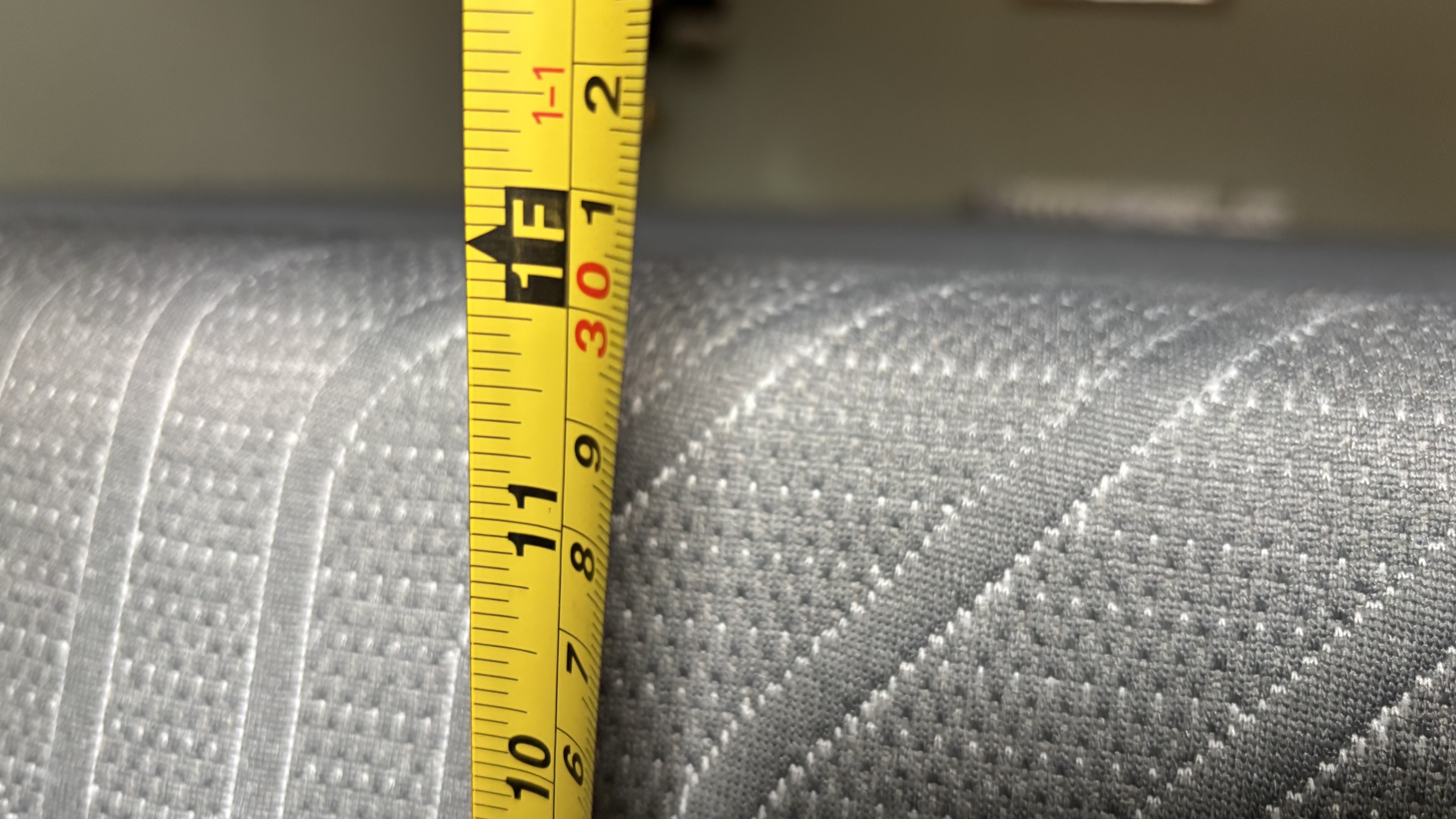 A measuring tape measures the height of the fully-expanded EGOHOME Black 12" Mattress.