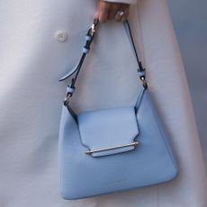 a close up of a woman holding a strathberry bag next to a white coat