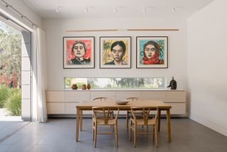 Three matching prints in matching frames on a wall behind a dining table
