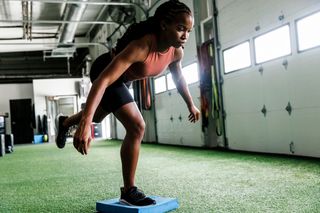 Woman balances on one leg on a foam pad in gym