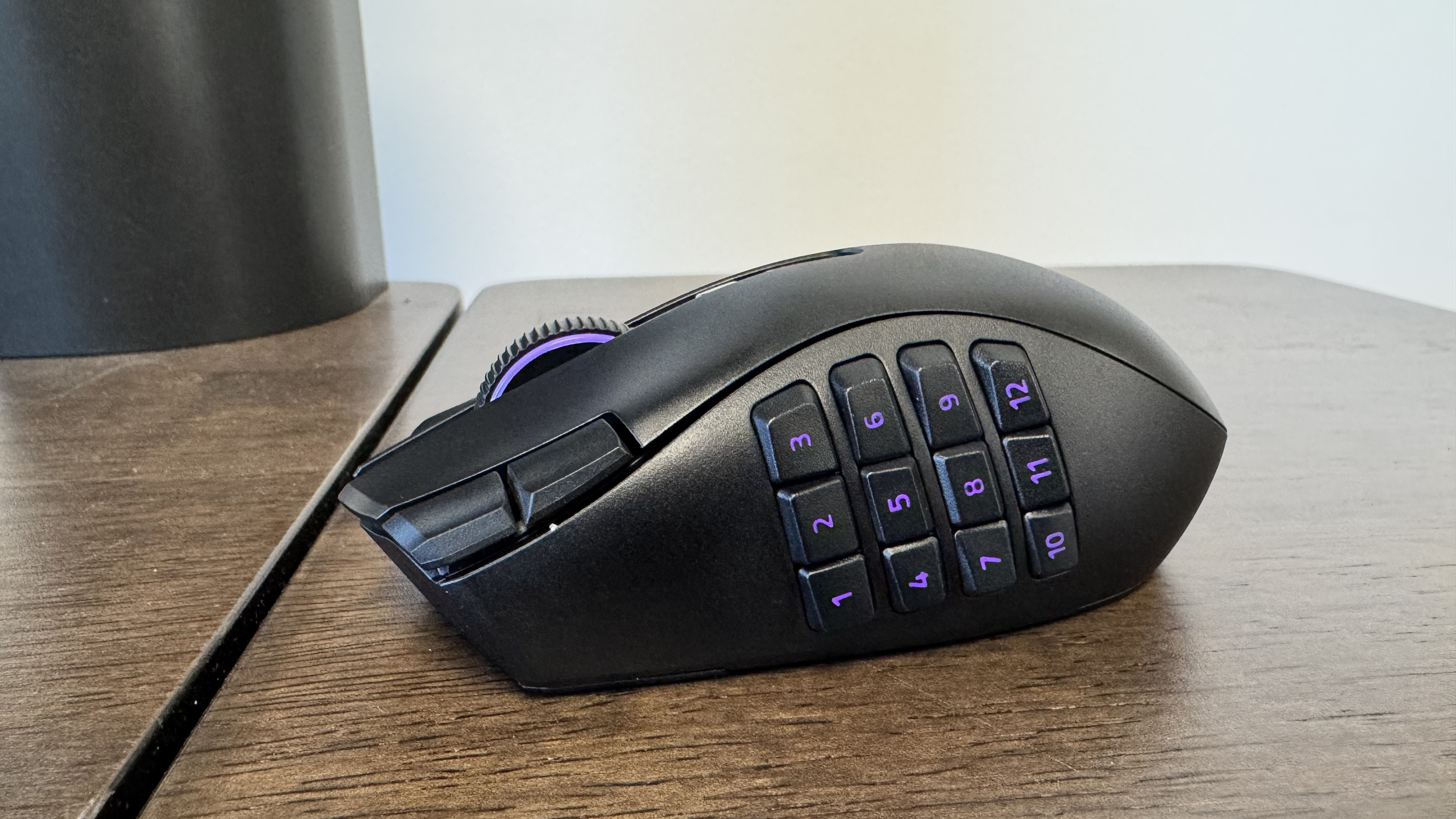 The Razer Naga V3 Pro on a wooden table from the left hand side, showing the 12 button faceplate