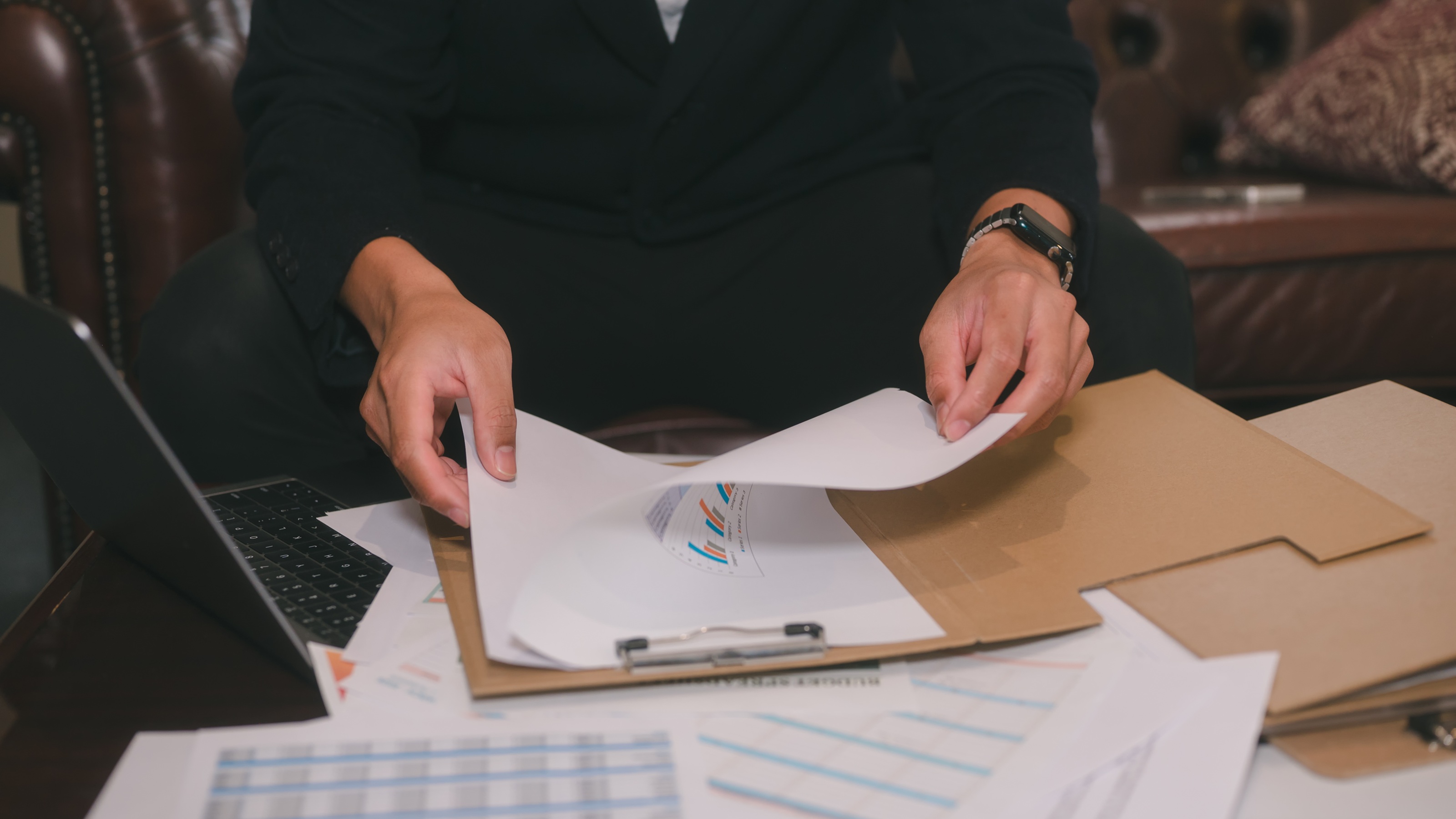 A man looks over financial paperwork, only his hands showing.