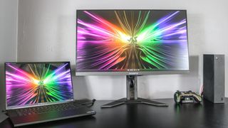 The Gigabyte M28U gaming monitor on a desk with an Xbox and gaming laptop