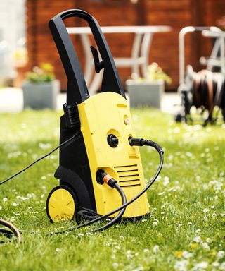 A yellow pressure washer sitting on a lawn
