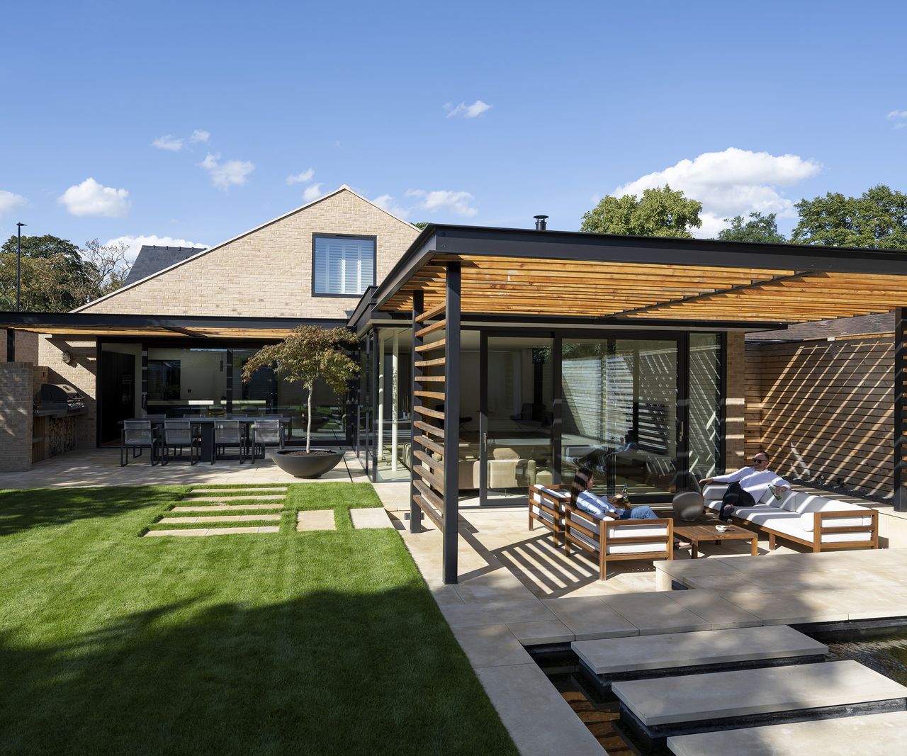 rear exterior of a renovated bungalow with covered patio area and fresh lawn