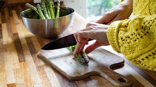 woman cutting asparagus on a board