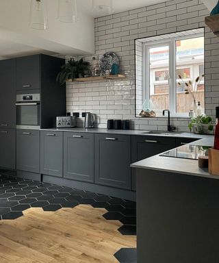 A newly renovated dark grey kitchen with wood floor partially tiled over with hexagonal black tile