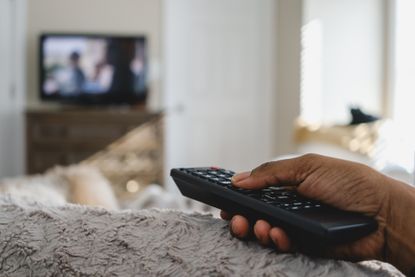 woman holding remote control while watching tv in bed