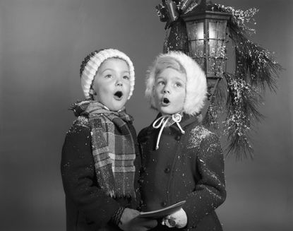 Two young carolers at a lamp post