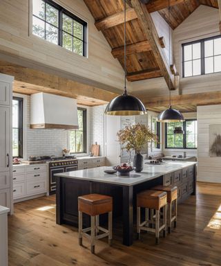 Wooden beams, black kitchen island, white countertops and cupboard