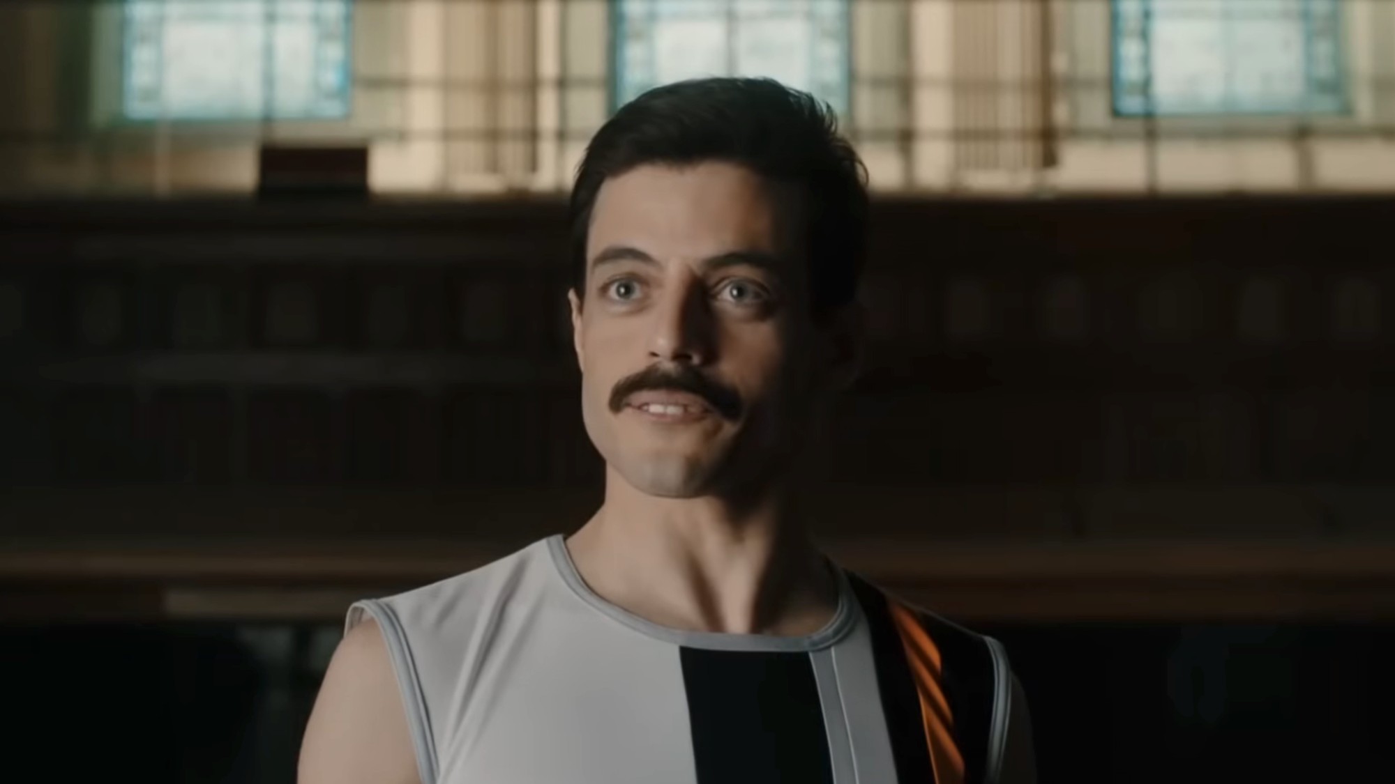 Rami Malek as Freddie Mercury with a mustache, telling his bandmates about his HIV diagnosis in Bohemian Rhapsody.