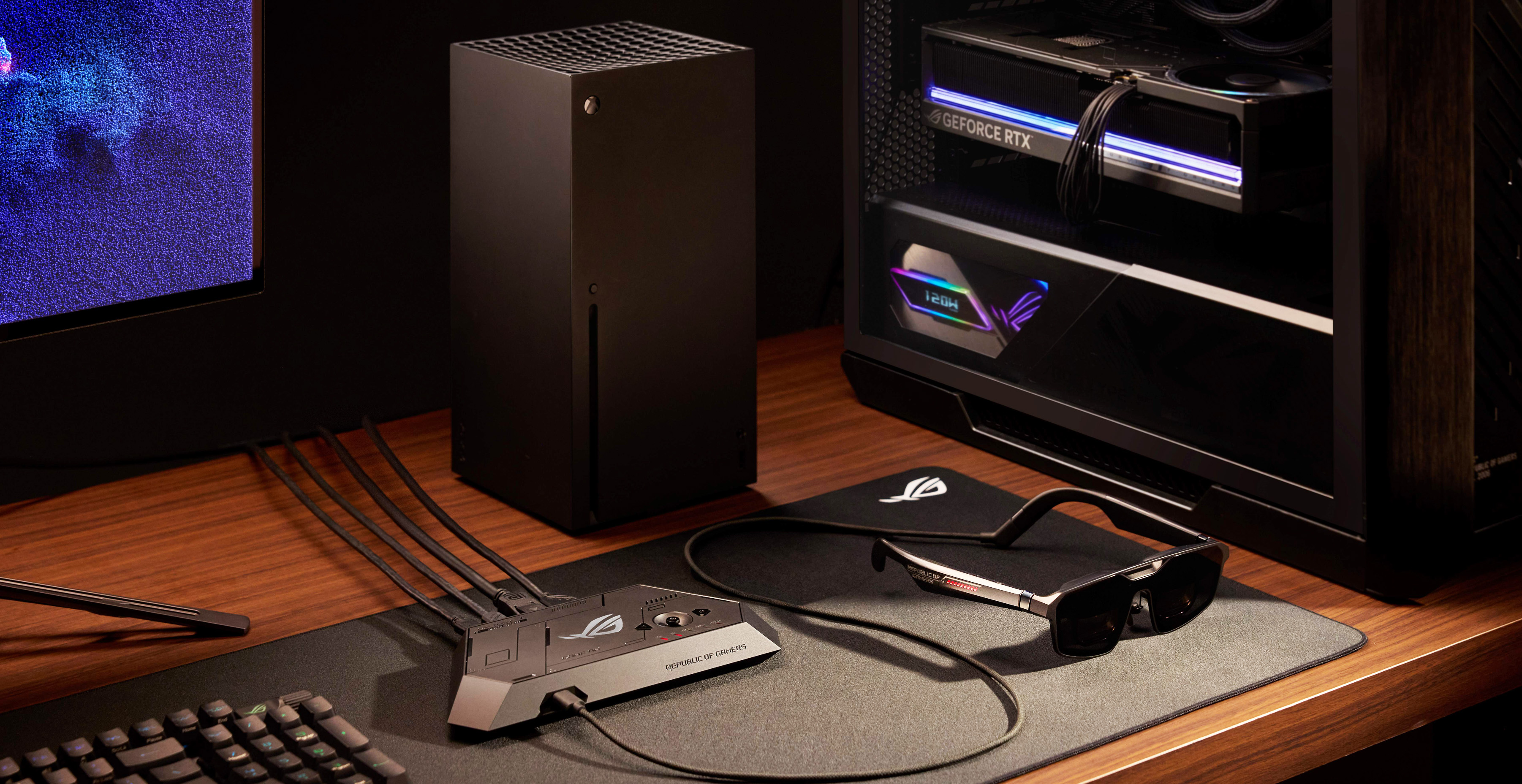 A high-tech gaming setup on a wooden desk, featuring a PC tower with glowing graphics card, a console, keyboard, and VR headset, evoking a sleek, modern vibe.