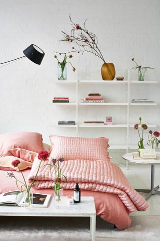 Designers Guild pink bedding in bedroom with shelves behind
