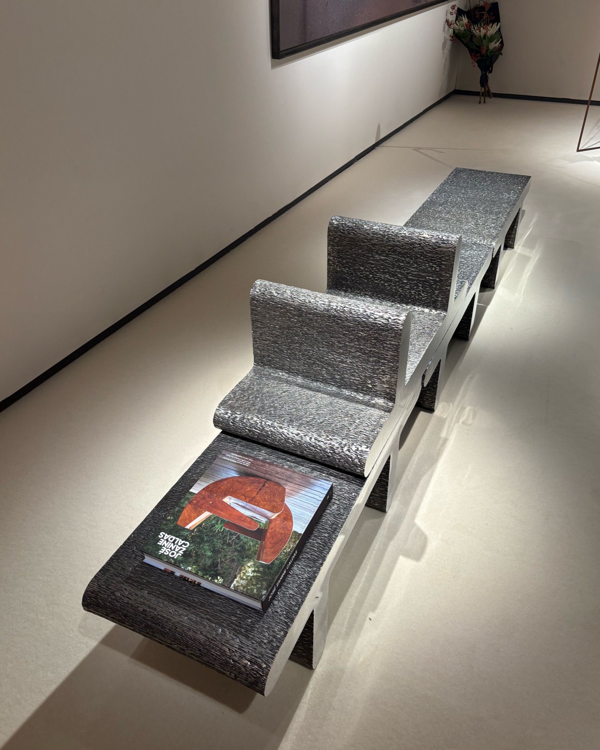 A series of contemporary furniture items with either a stitched-up or a tetris-looking structure sits in a warmly lit gallery space.