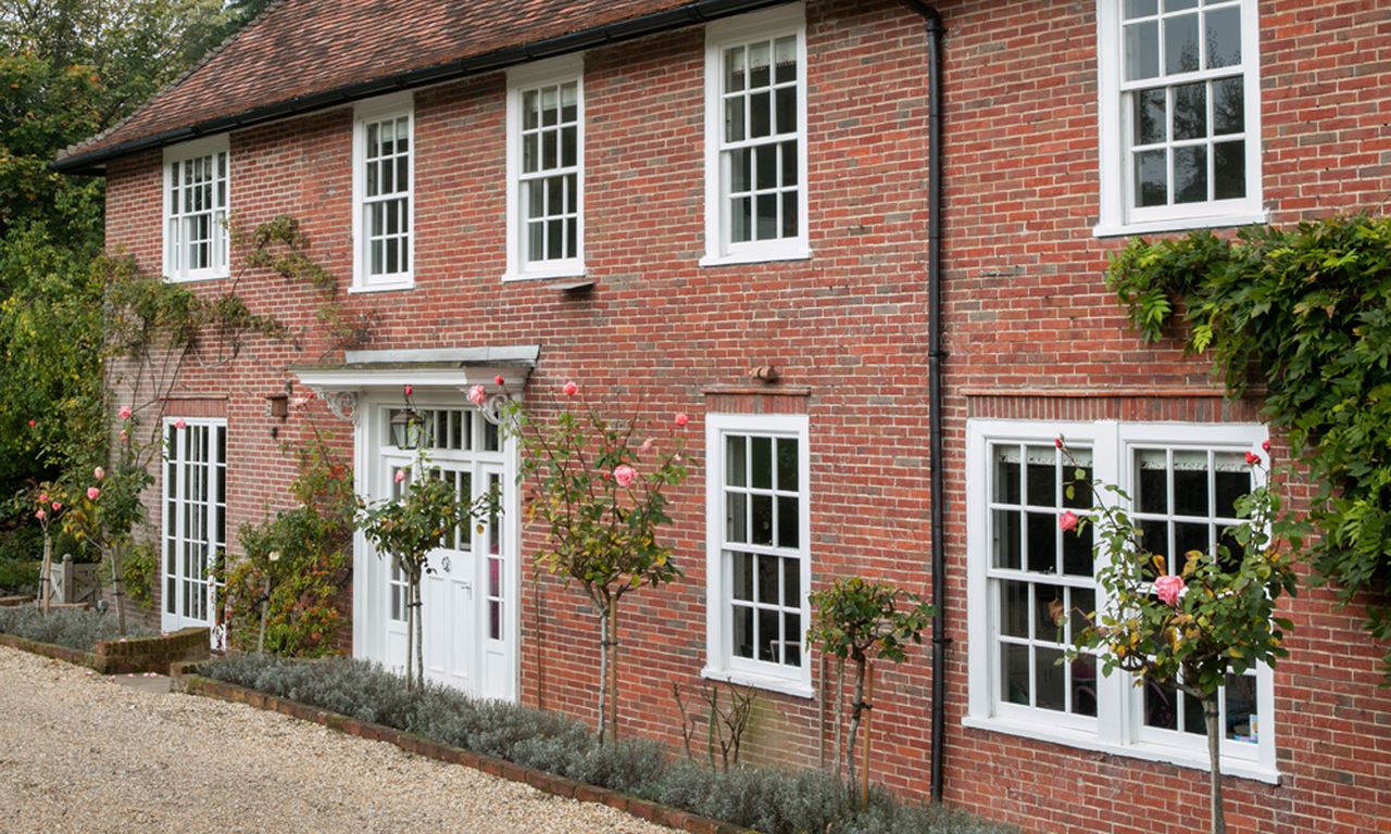 Exterior of house with white window frames and brick wall