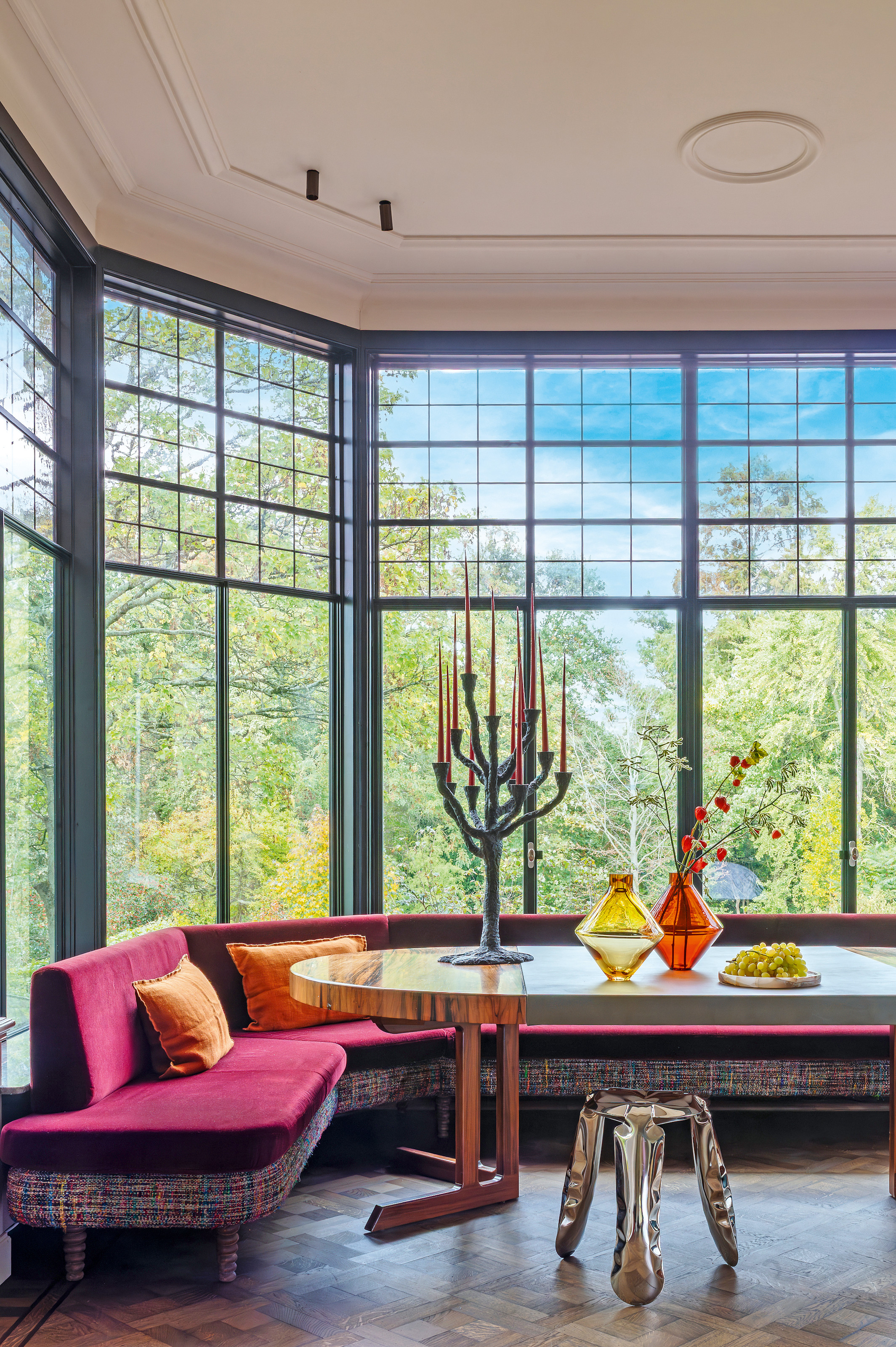 Dining room with pink upholstered banquette seating around an oval lacquered dining table with a chrome stool