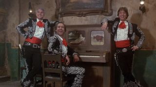 Steve Martin, Chevy Chase and Martin Short smiling by a piano in Three Amigos