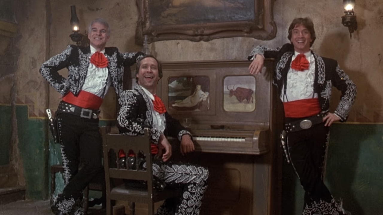 Steve Martin, Chevy Chase and Martin Short smiling by a piano in Three Amigos