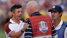 Rory McIlroy of Team Europe speaks with caddie of Patrick Cantlay of Team United States (not pictured), Joe LaCava on the 18th green during the Saturday afternoon fourball matches of the 2023 Ryder Cup at Marco Simone Golf Club on September 30, 2023 in Rome, Italy.