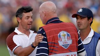 Rory McIlroy of Team Europe speaks with caddie of Patrick Cantlay of Team United States (not pictured), Joe LaCava on the 18th green during the Saturday afternoon fourball matches of the 2023 Ryder Cup at Marco Simone Golf Club on September 30, 2023 in Rome, Italy.