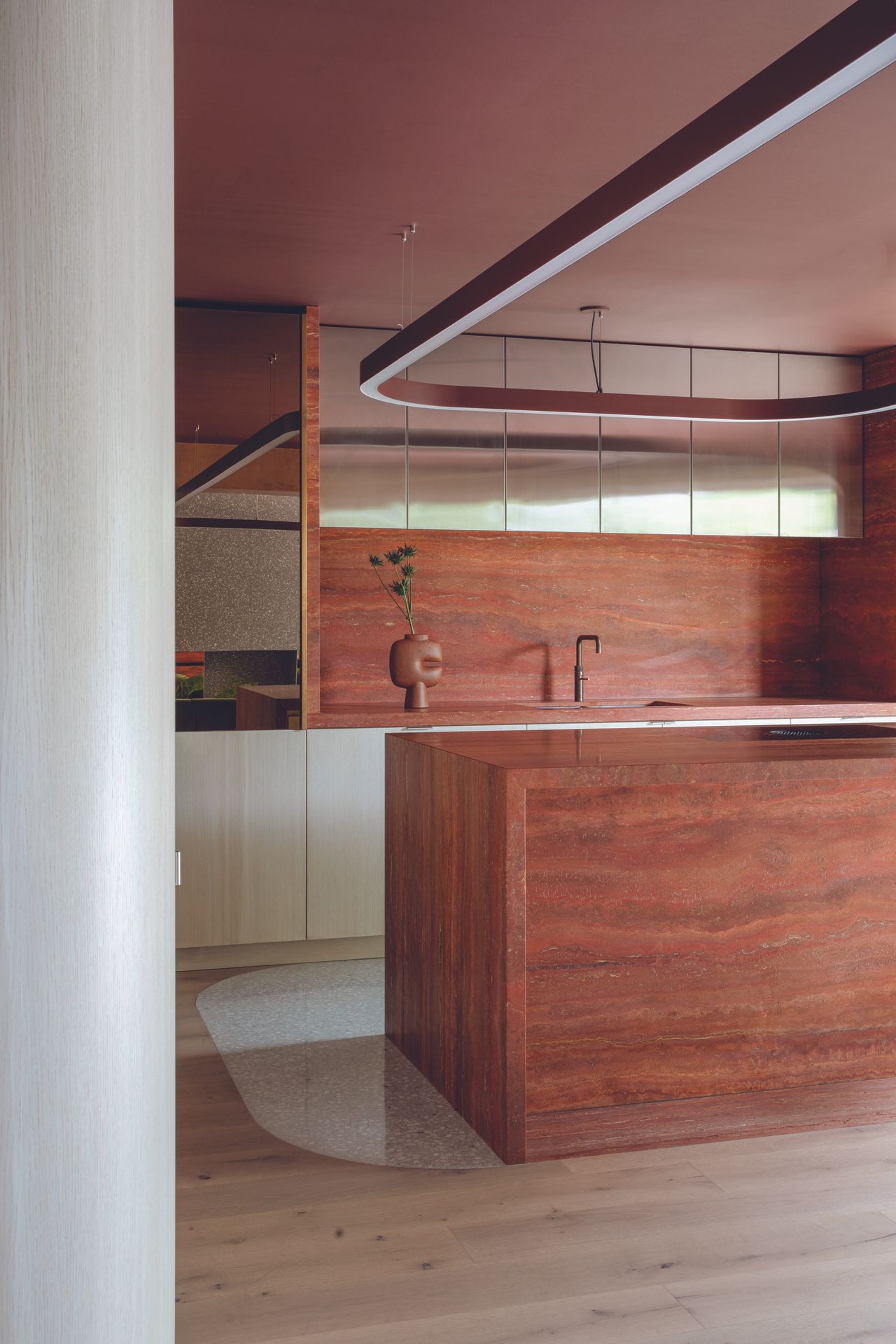 An Earthy-textured kitchen island with metallic overhead cupboards