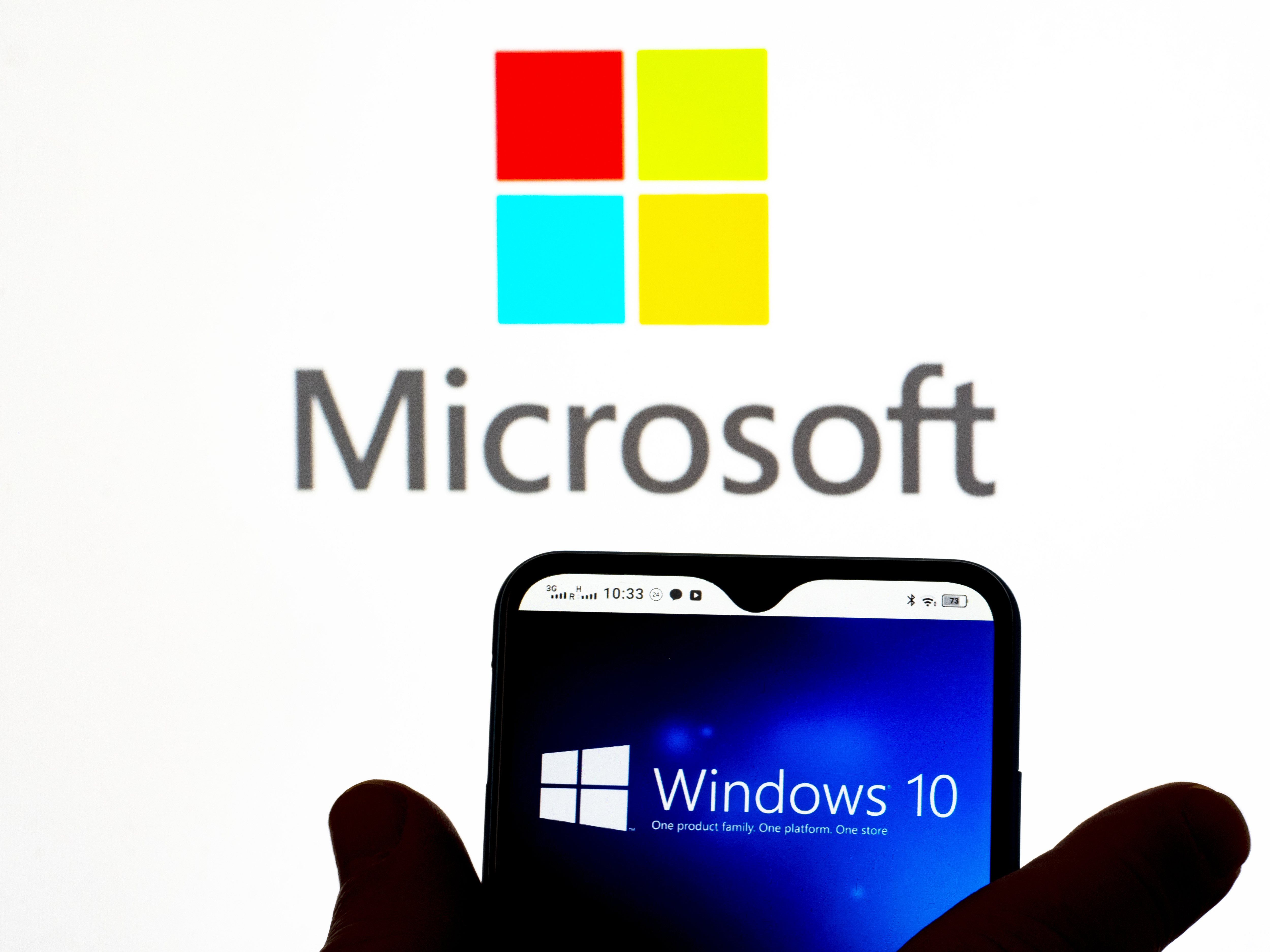 Windows 10 logo displayed on a smartphone with Microsoft branding in background