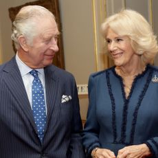 King Charles and Queen Camilla smiling at each other in blue outfits