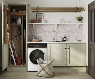 sage green cupboards in utility with washer and dryer stacked in a floor to ceiling cupboard