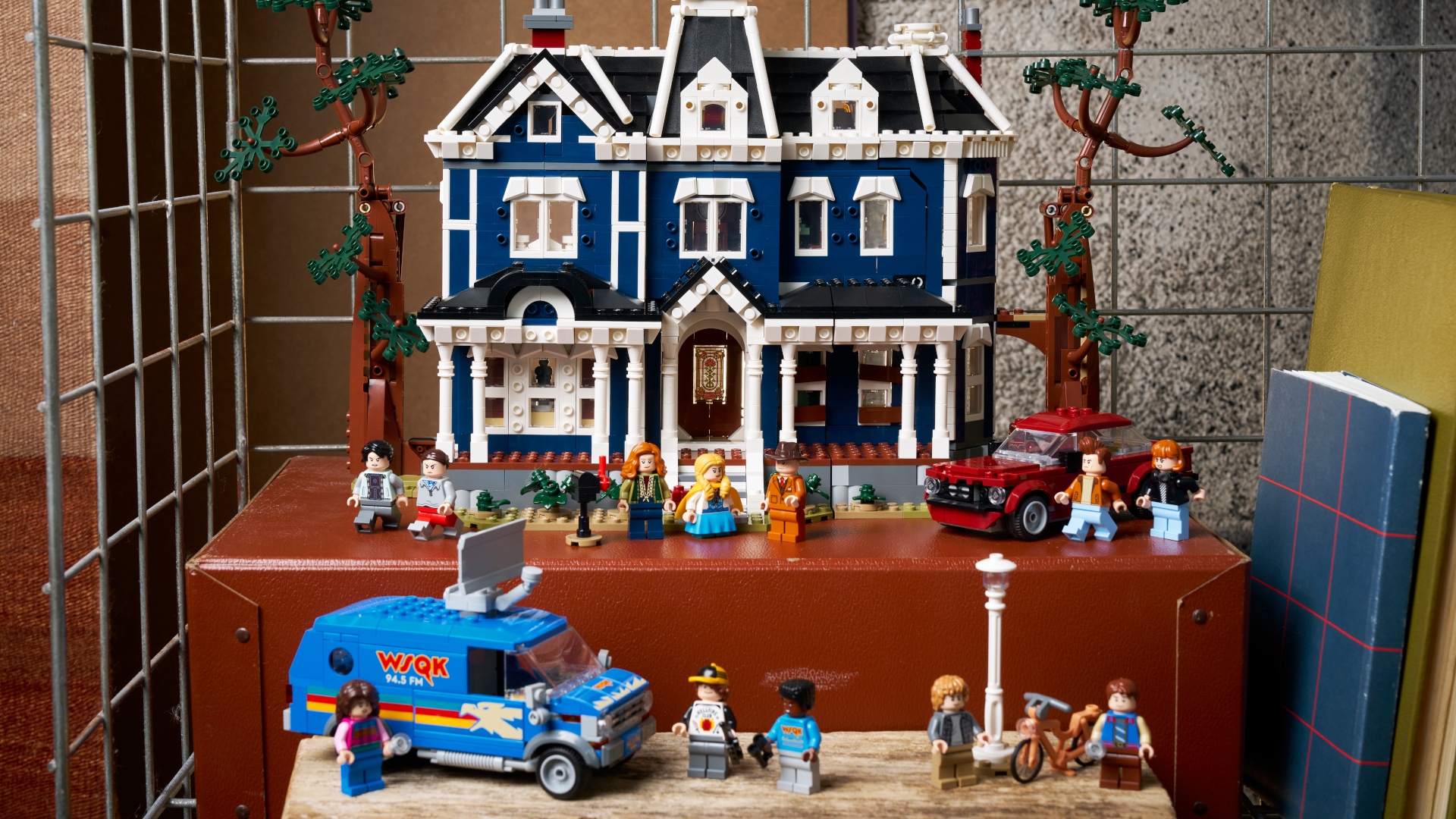 The Lego Creel House set, minifigures, and accessories on trunks in a caged shelving unit