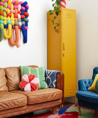 bright playroom with tan couch, yellow storage unit, knitted artwork, bright cushions