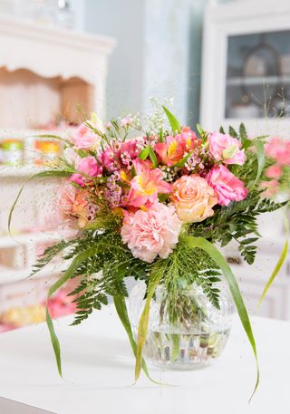 composition of pink flowers including roses and lilies in glass vase in pretty vintage-style dining room