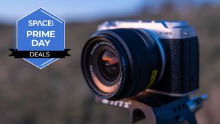 A Fujifilm X-M5 with XF 15-45mm OIZ PZ lens attached in a field with a blue Space.com Prime Day badge in the upper left corner.